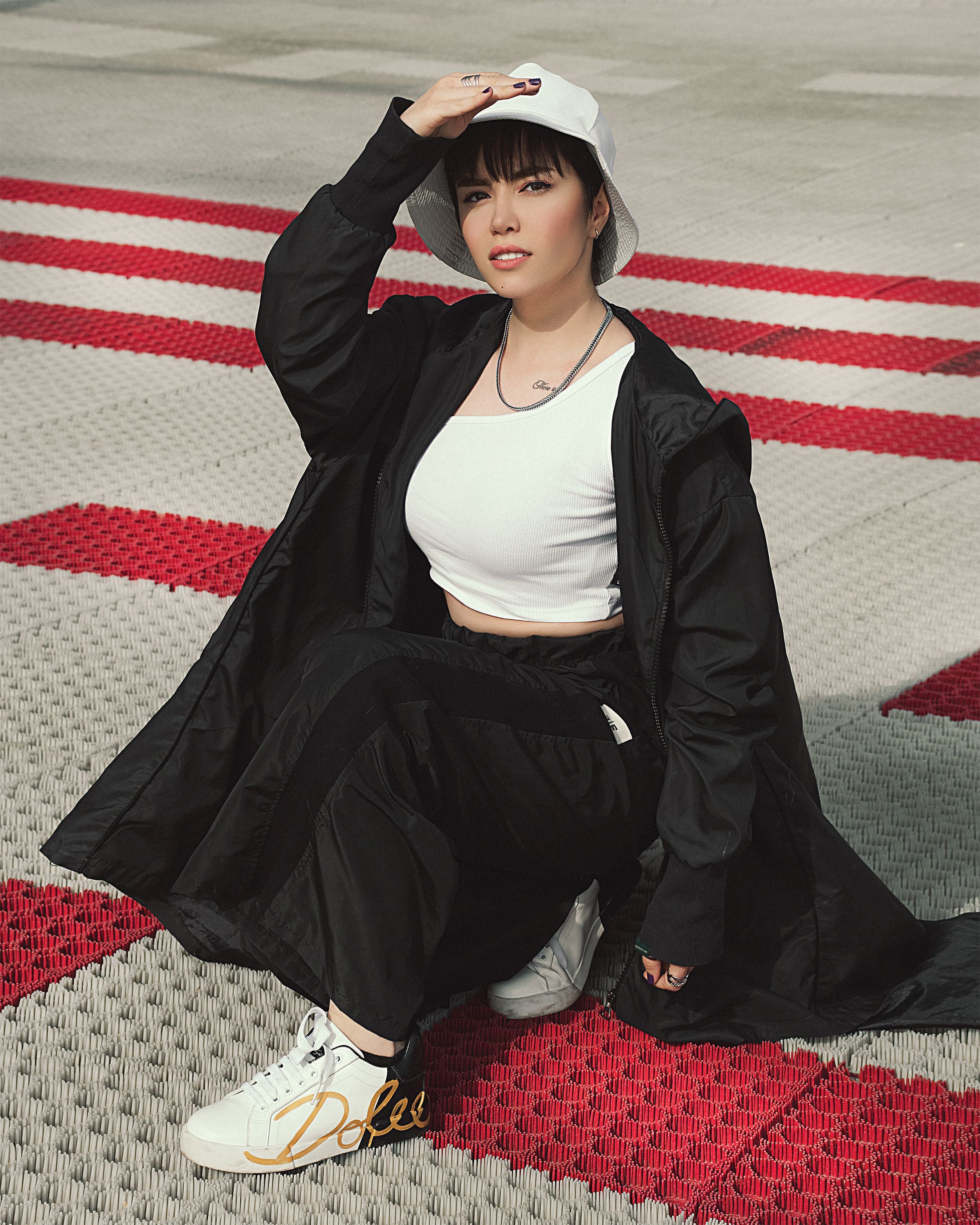 Woman in stylish streetwear crouching outdoors, showcasing modern urban fashion with bold patterns.