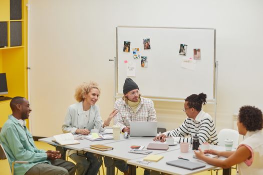 A group of diverse colleagues discussing ideas in a bright office setting.