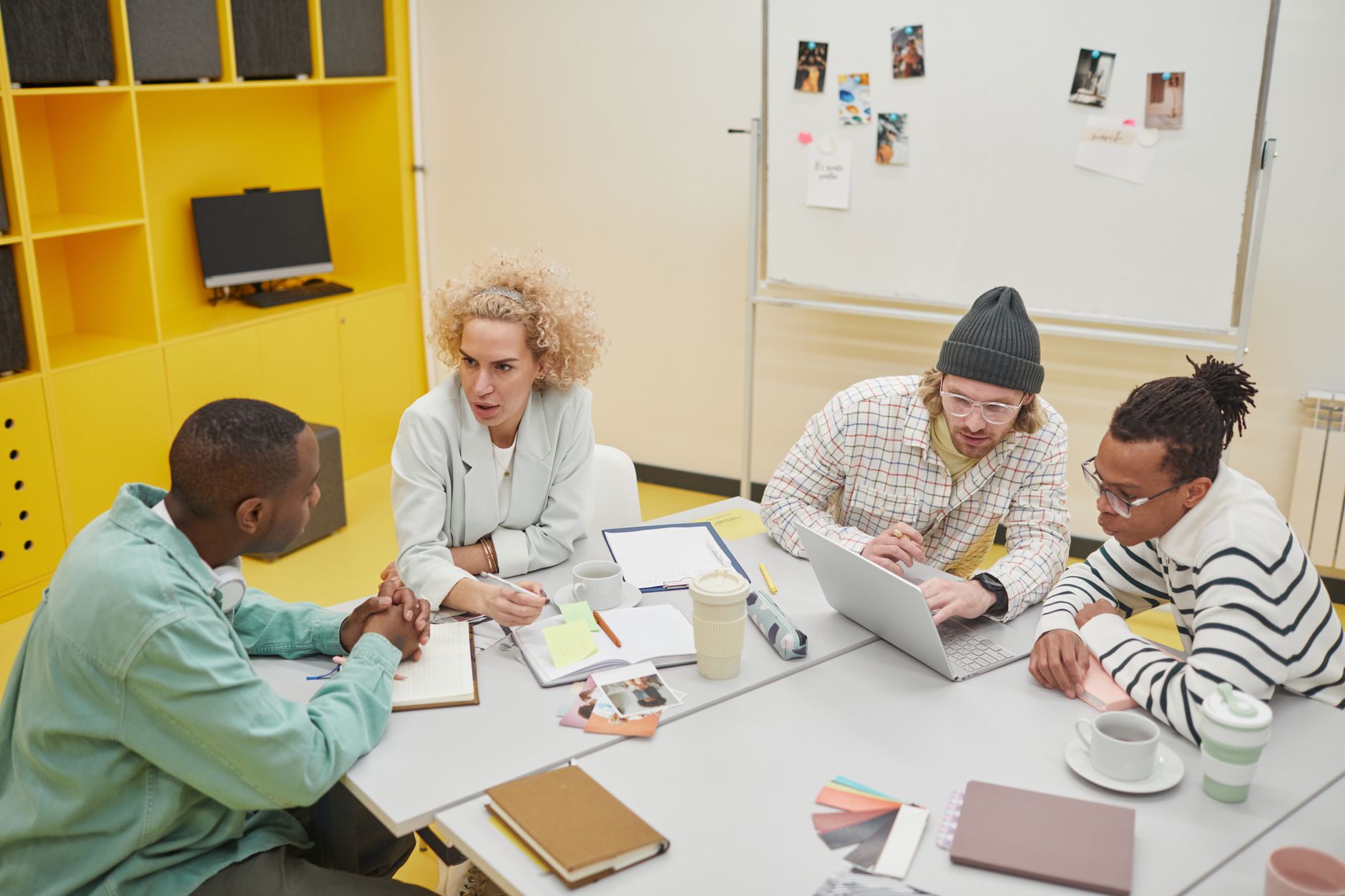 Diverse group of colleagues discussing ideas and collaborating in a bright, modern office setting.