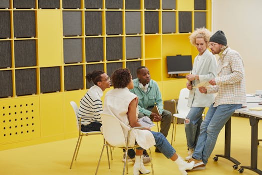 Group of coworkers engaged in a meeting in a vibrant, yellow office environment.