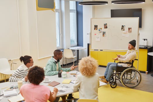 Diverse team engaged in a collaborative office meeting with a presenter in a wheelchair explaining ideas.