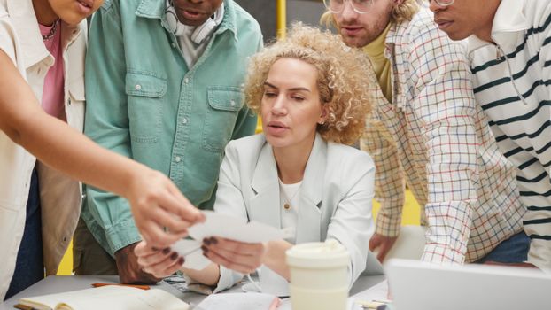 Group of diverse adults collaborating on a project in a modern workspace.