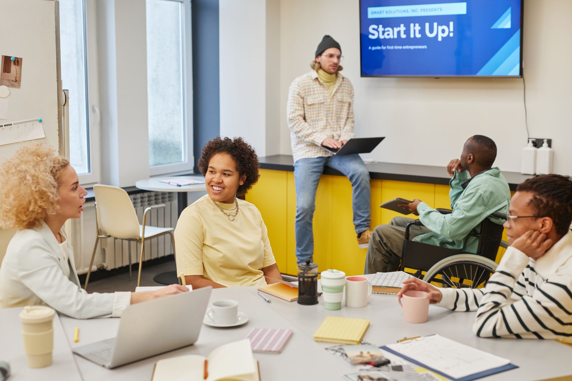 A diverse team in a modern office discussing a startup project during a workshop with a digital presentation.