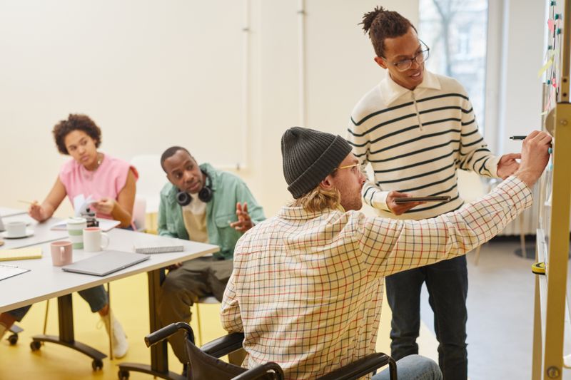 A diverse group of people, including individuals with disabilities, collaborating in a team meeting.
