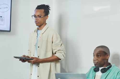 Free Two men in a modern office discussing with technology and screens, promoting teamwork and innovation. Stock Photo