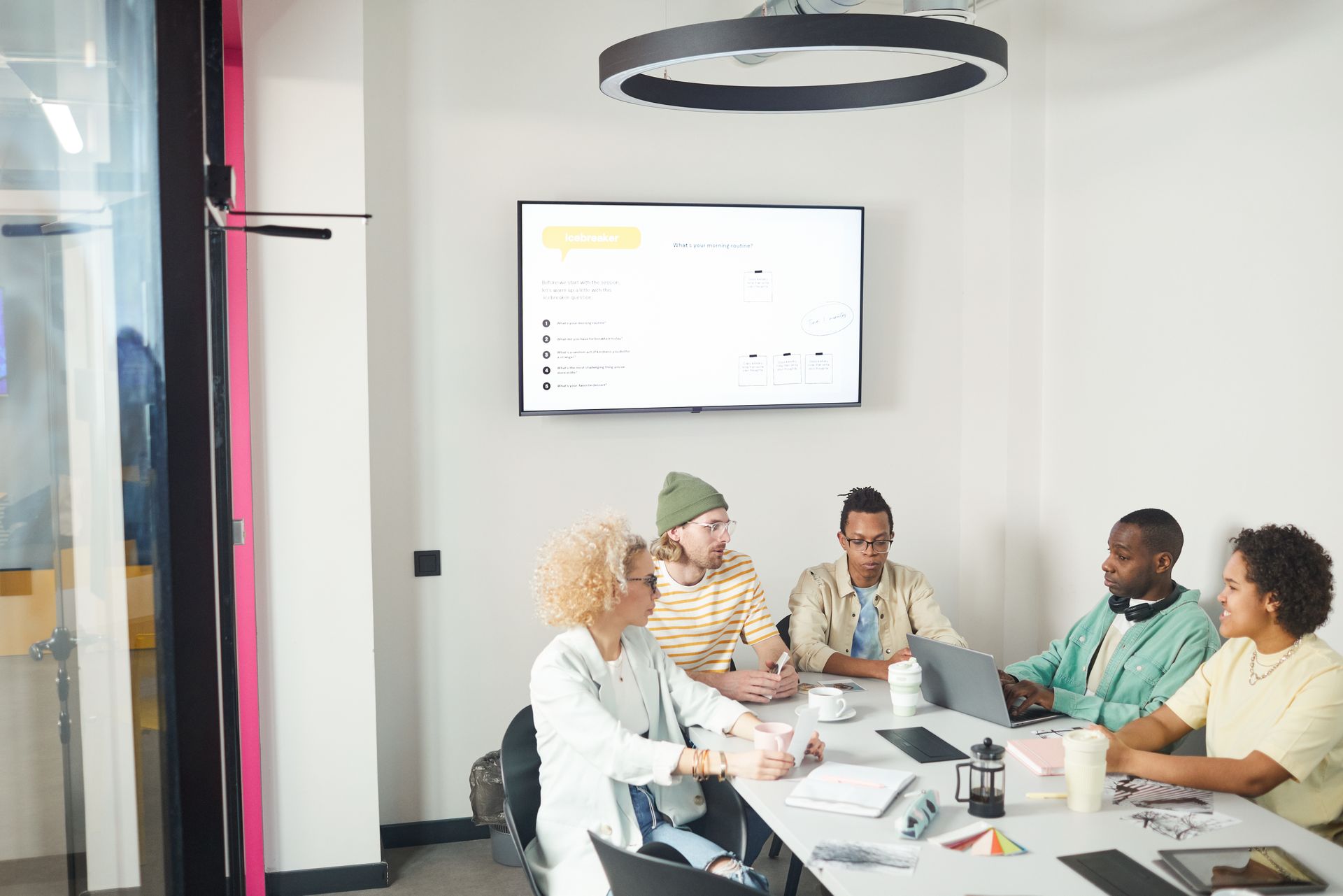 Group of diverse coworkers in discussion during a business meeting in a modern office setting.