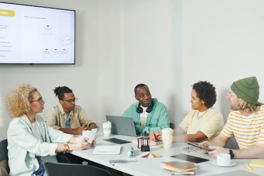 A diverse team of coworkers brainstorming in a modern office setting around a table.