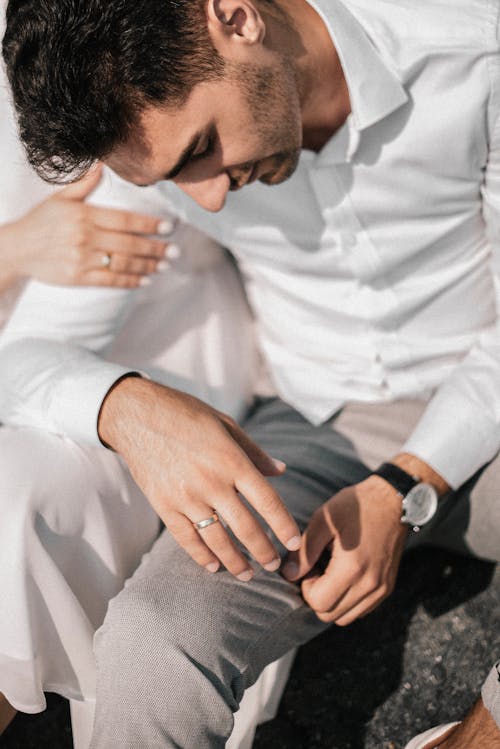 A Person Touching the Arm of a Man in White Long Sleeve Shirt 
