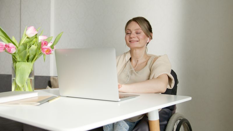 A smiling individual using adaptive technology to assist with daily tasks.