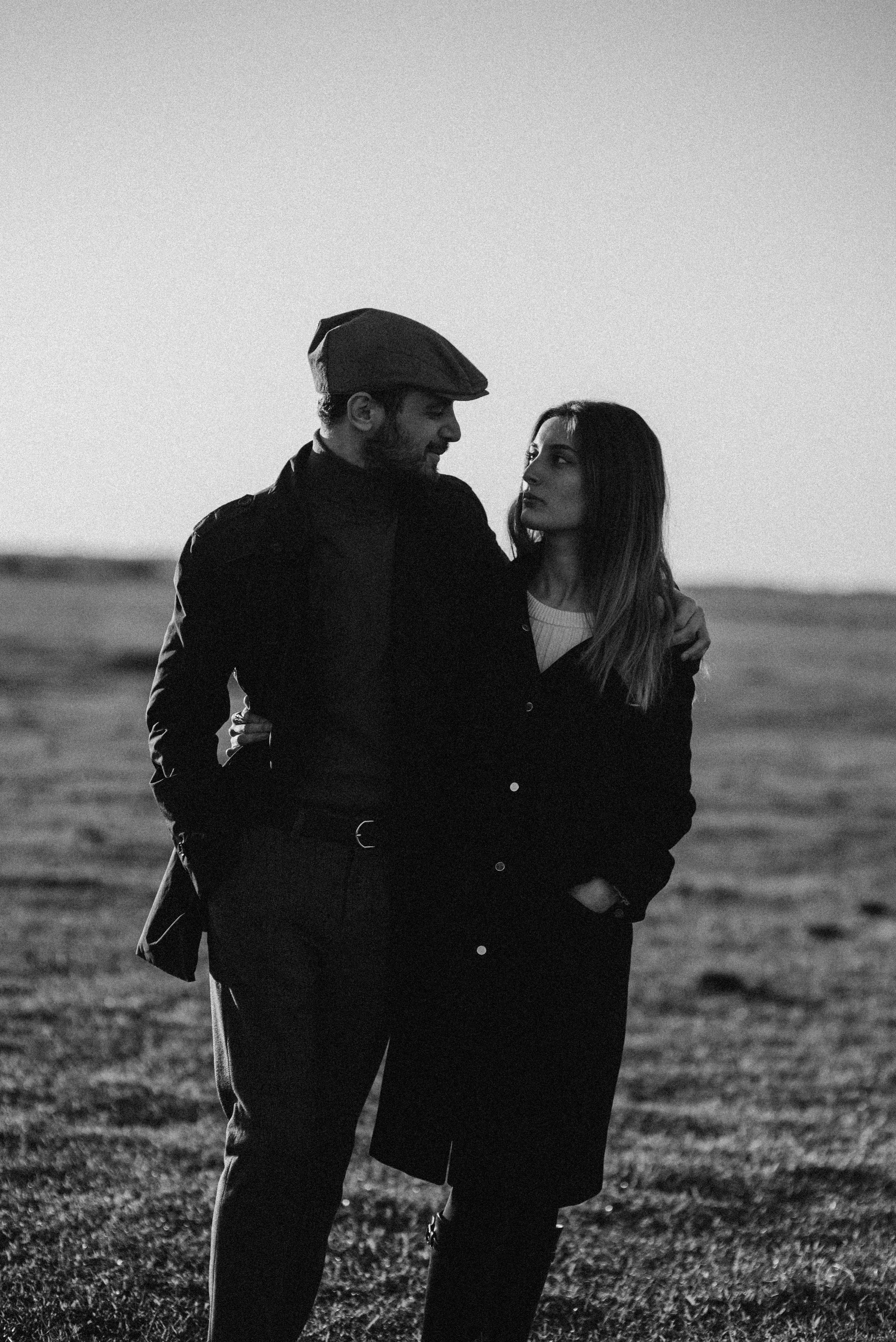 Monochrome image of a couple walking together outdoors, sharing a warm embrace.