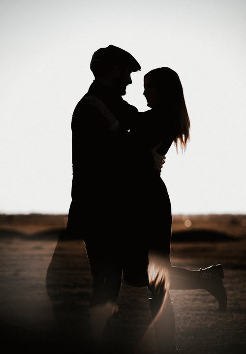 Silhouette of Man and Woman Kissing on Beach during Sunset