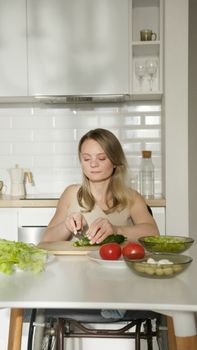 A woman cuts fresh vegetables in a bright kitchen setting, embracing healthy eating habits.