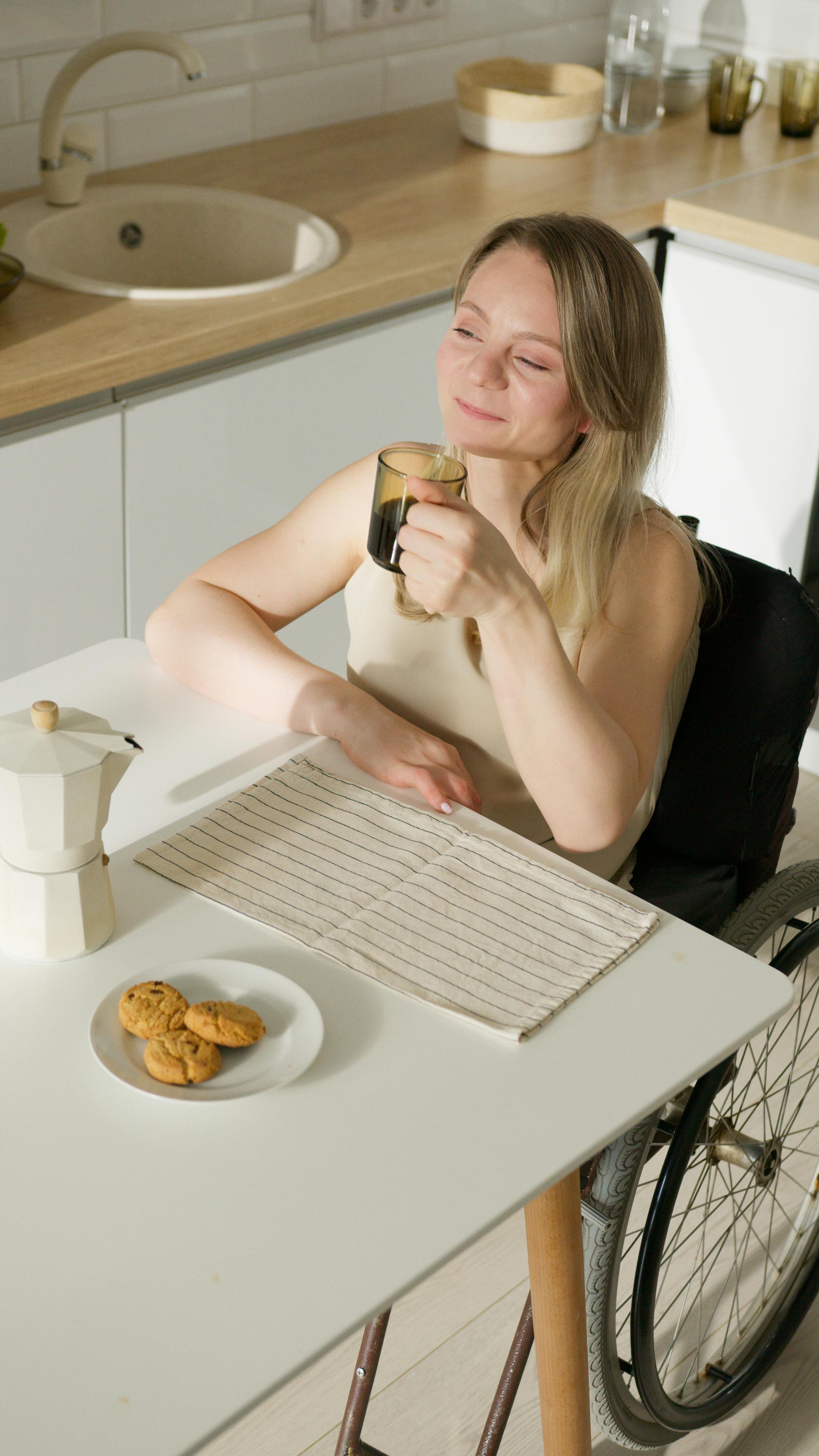 a woman in beige tank top holding a cup of coffee