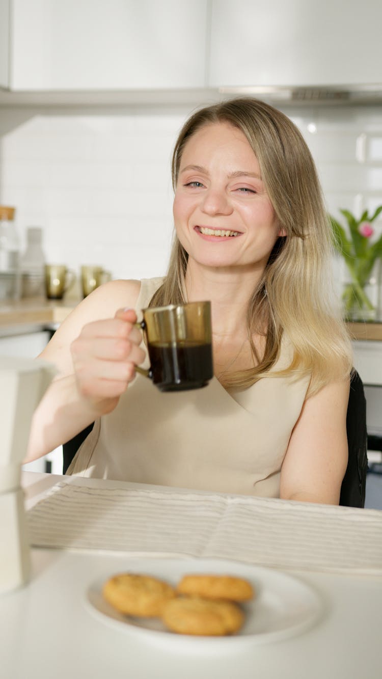 A Woman Holding A Clear Glass Coffee Cup With Black Beverage