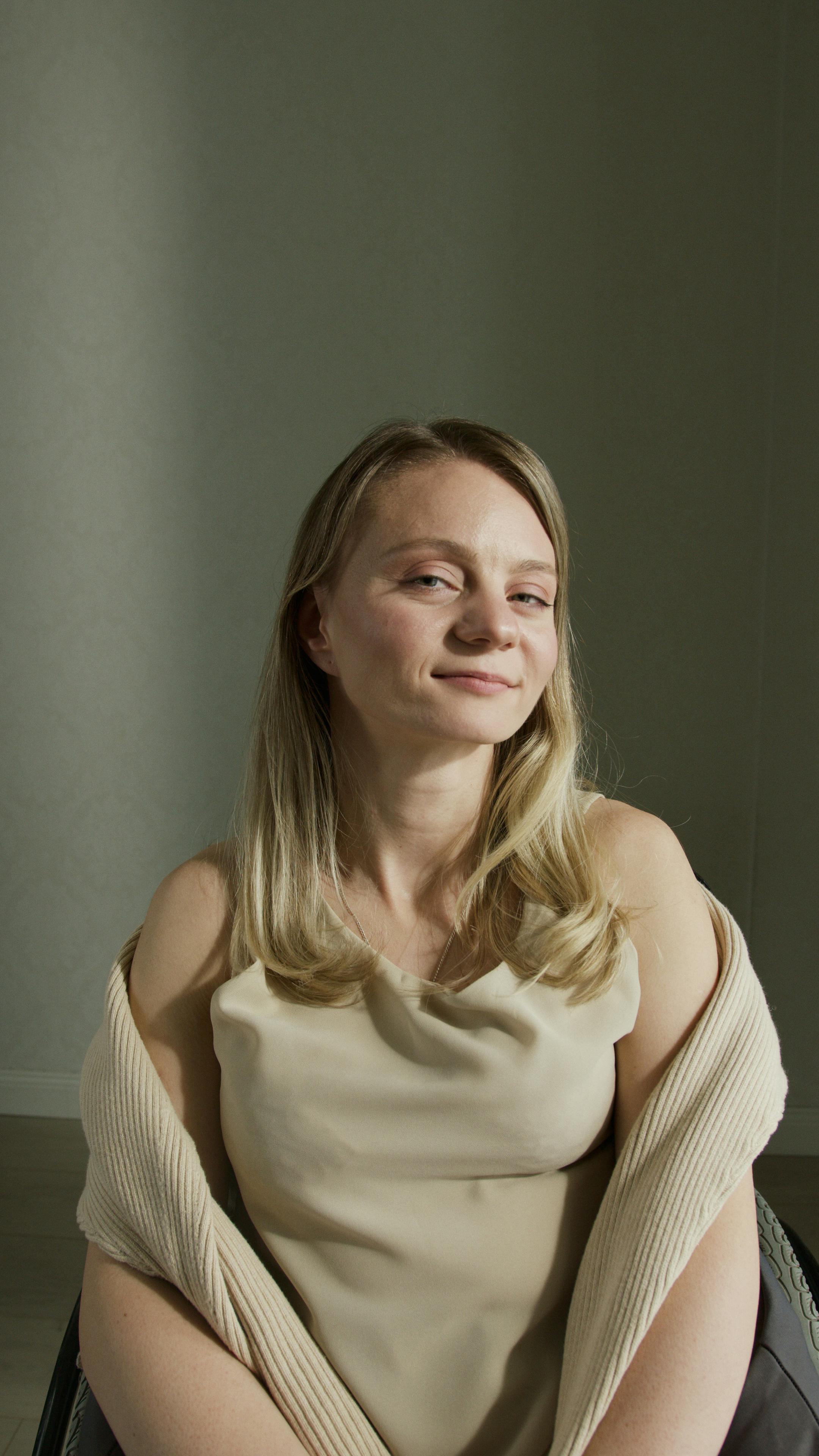 Sophisticated portrait of a confident Caucasian woman with blonde hair, taken indoors with soft lighting.