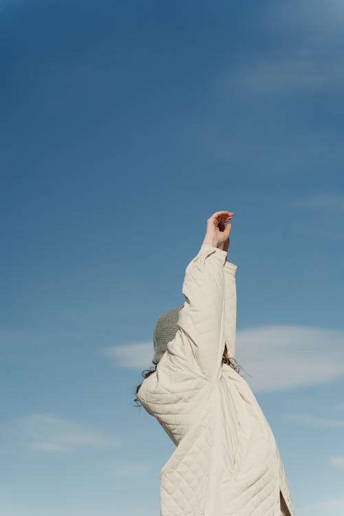 Person in White Jacket Standing Under Blue Sky