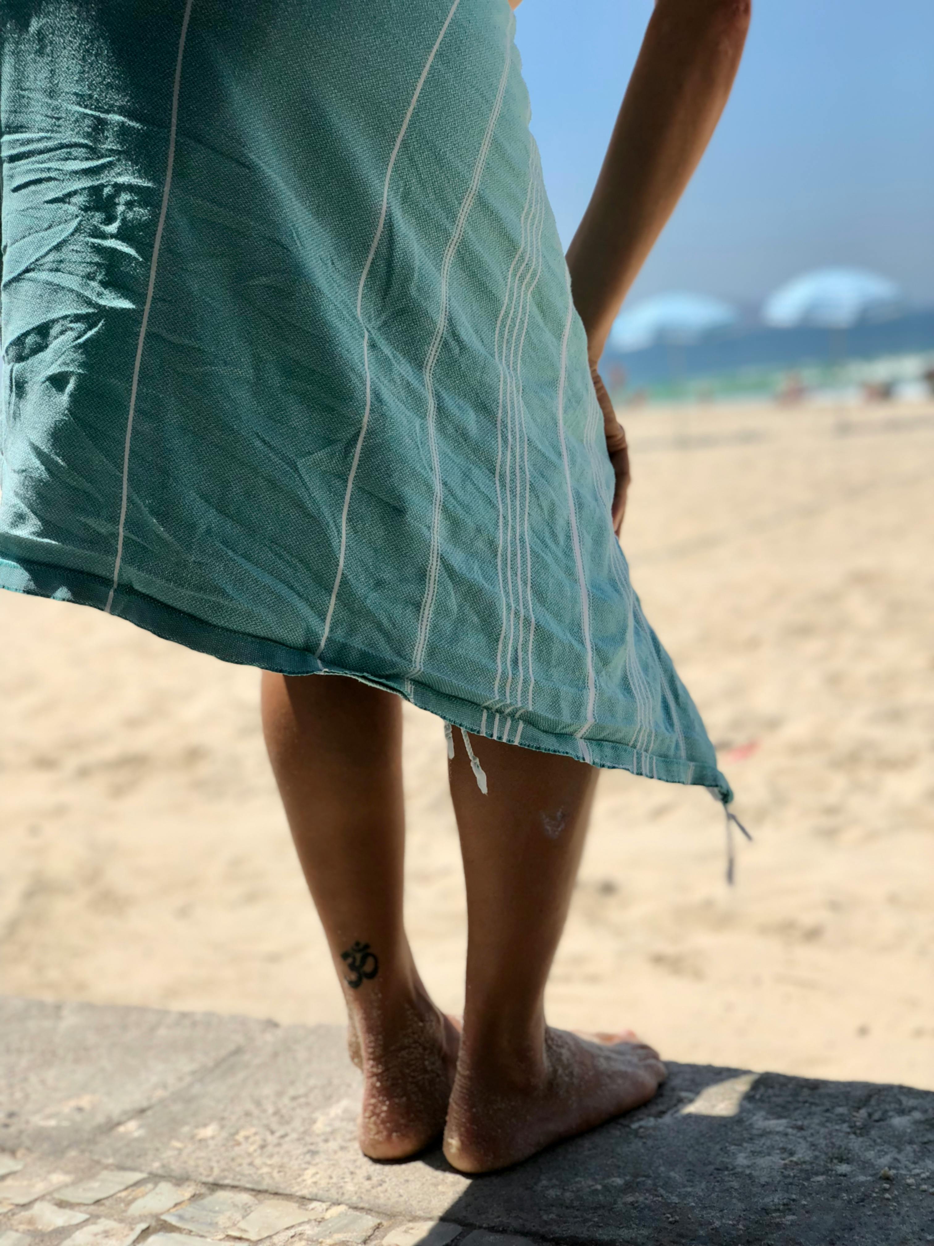 Close-up of a person standing barefoot with a tattoo on Leblon Beach, Rio de Janeiro.