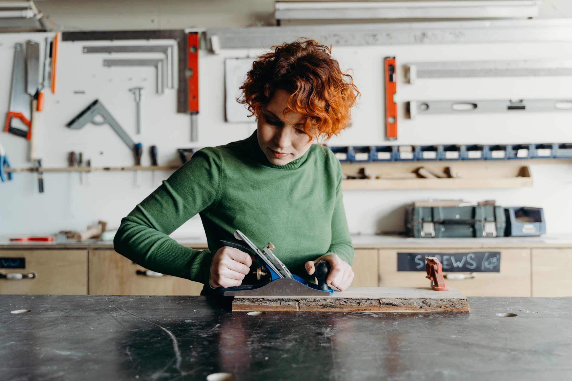 Female woodworker shaping timber inside a professional workshop