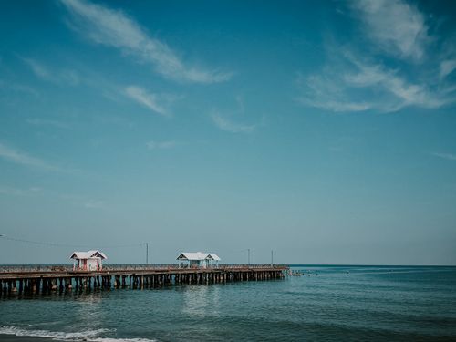Free Serene ocean scene featuring a long pier extending into the calm sea under a blue sky. Stock Photo