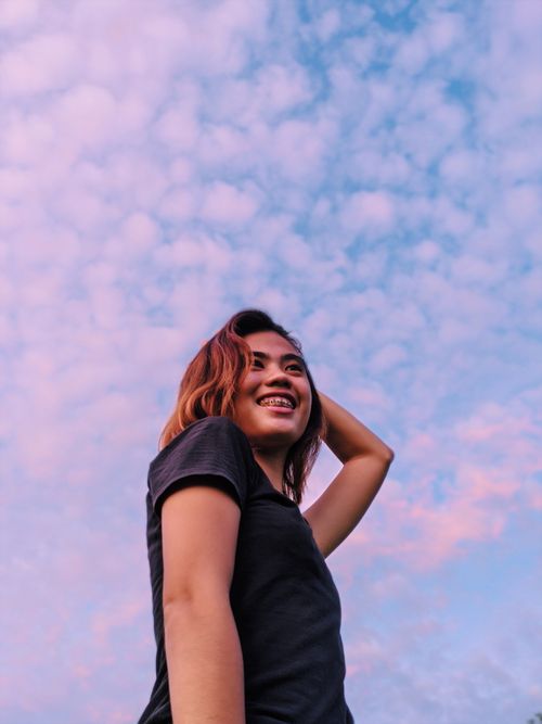 Free Asian woman smiling beneath a vibrant sky in Bulalacao, Philippines. Captured with a low-angle shot. Stock Photo
