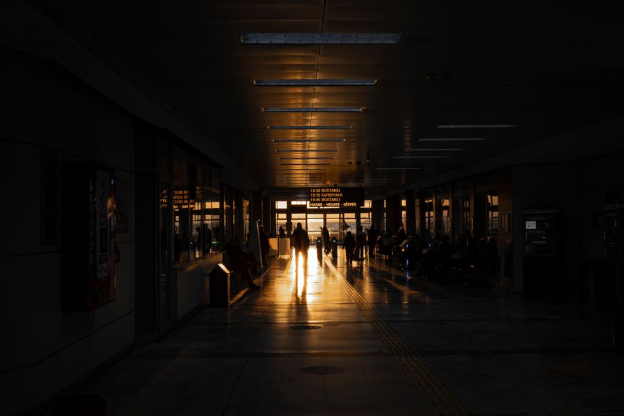 Travelers walking through an airport terminal in İzmir, Türkiye, during a stunning sunset casting long shadows.