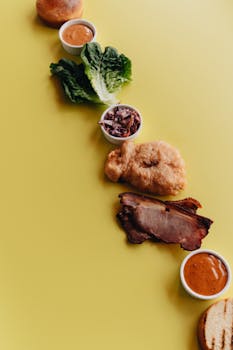 Aerial view of deconstructed burger ingredients on a vibrant yellow surface.