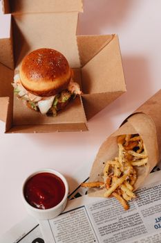 Delicious gourmet burger with crispy fries served in eco-friendly box, perfect for fast food lovers.