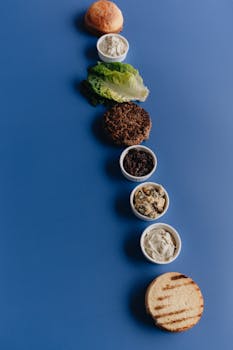 Flat lay of a deconstructed burger with ingredients on a blue background, perfect for creative food photography.