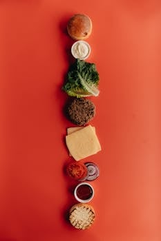 Top-down view of burger ingredients arranged on a vibrant red background.