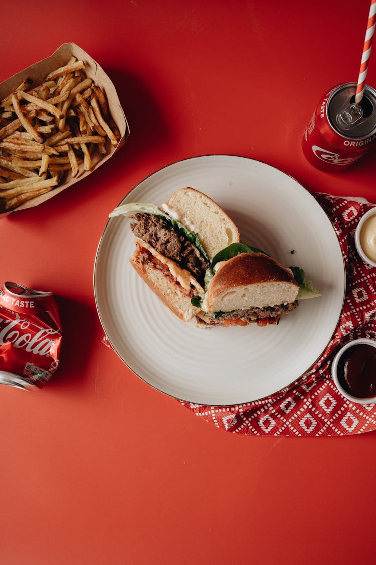 Burger On White Ceramic Plate Beside Fries And Soda