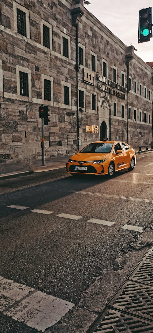 Yellow Car on a Street in Front of Buildings 