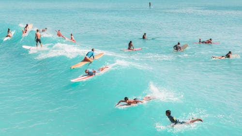 People Surfing in the Blue Sea During Summer 