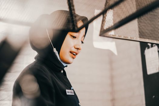 Charming young woman wearing a hijab, engaged in work indoors with a bright, welcoming expression.