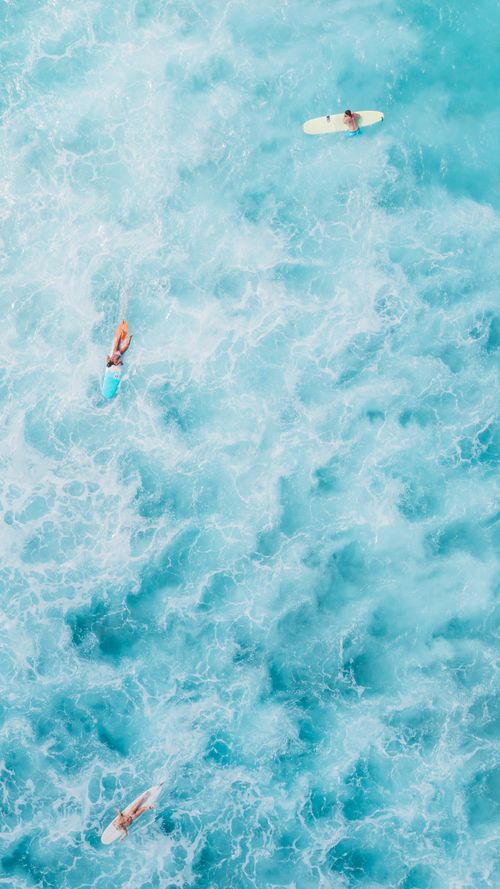 Free Aerial view capturing surfers navigating vibrant turquoise ocean waves, showcasing summer adventure. Stock Photo