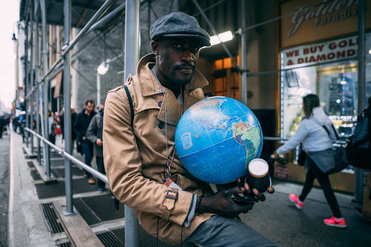 Man Wearing A Flat Cap Holding A Globe