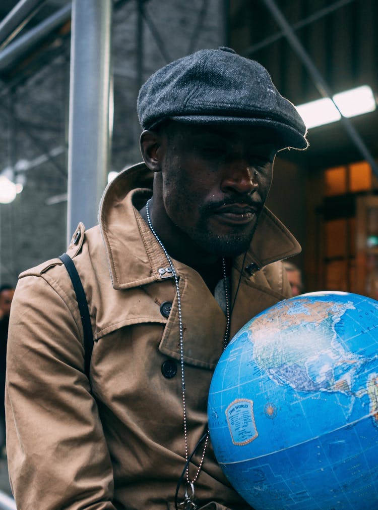 Man In Brown Overcoat Holding A World Globe