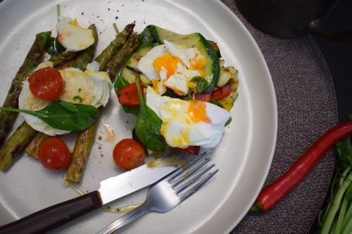 Free Delicious meal featuring poached eggs, asparagus, spinach, cherry tomatoes on a ceramic plate. Stock Photo