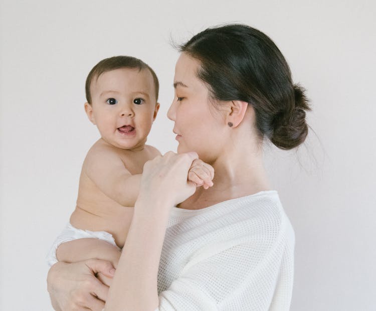 Woman In White Knit Sweater Carrying Baby