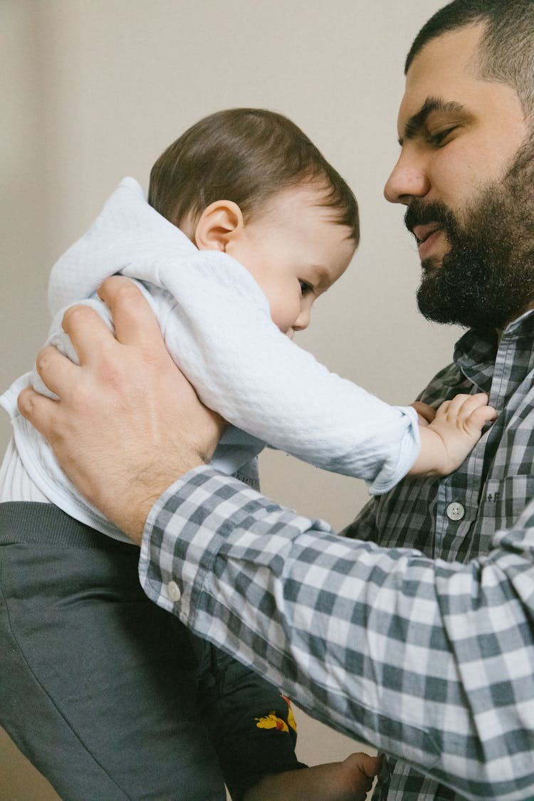 Man In Checkered Long Sleeves Carrying A Baby