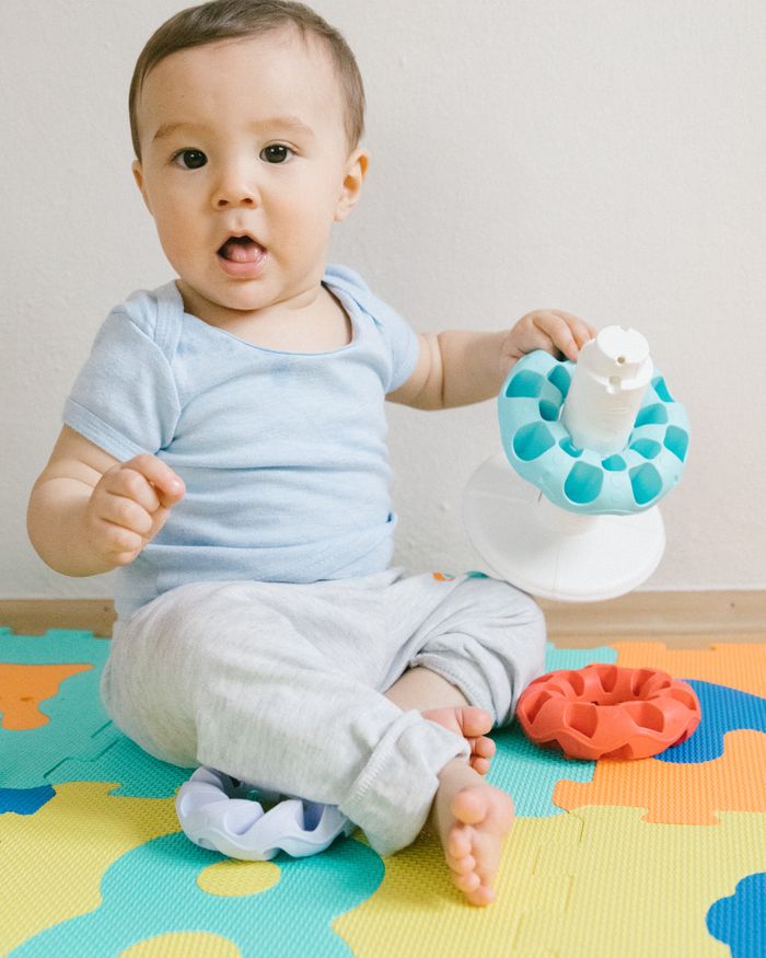 A baby playing with toys on a colourful play mat