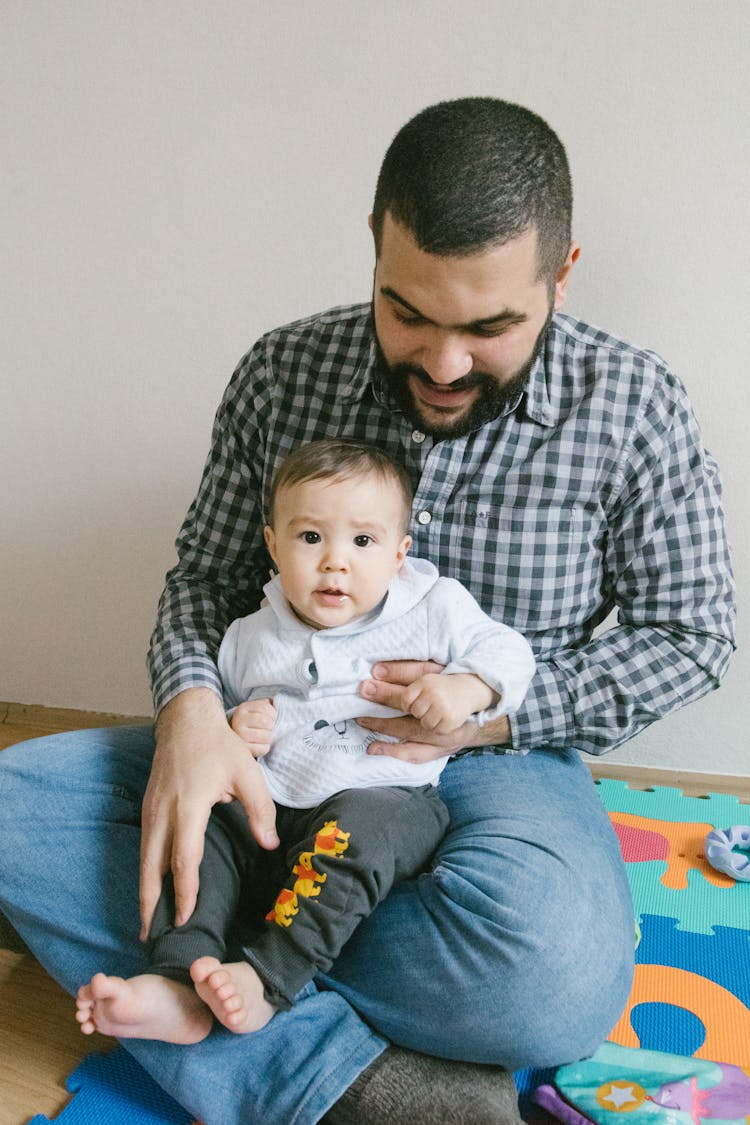 Man In Black And White Shirt Carrying Baby