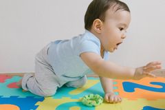 Adorable baby boy crawling on a vibrant puzzle mat indoors, showcasing childhood innocence and play.