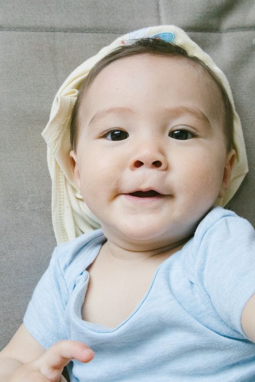 Free Charming baby boy lying indoors with a playful expression, capturing innocence and joy. Stock Photo
