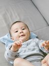 Baby in Blue Long Sleeve Shirt Lying on Gray Textile
