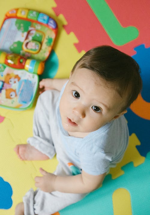 Free Baby in White Shirt Sitting on Puzzle Mat Stock Photo