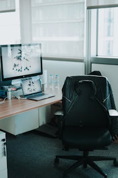 A clean, modern office setup featuring a desk with laptop, monitor, and office chair.