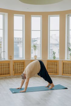 Elderly man doing yoga exercise indoors on a mat for fitness and wellness.