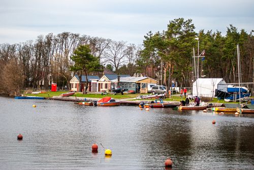 Free Tranquil riverside scene with docked motorboats and vibrant village backdrop. Stock Photo