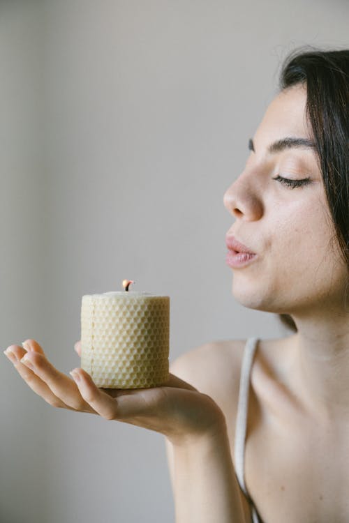 Woman Blowing A Lighted Candle