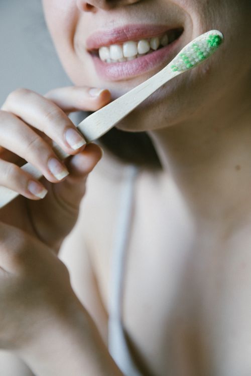 Free Close-up of a woman using an eco-friendly wooden toothbrush for dental care. Stock Photo